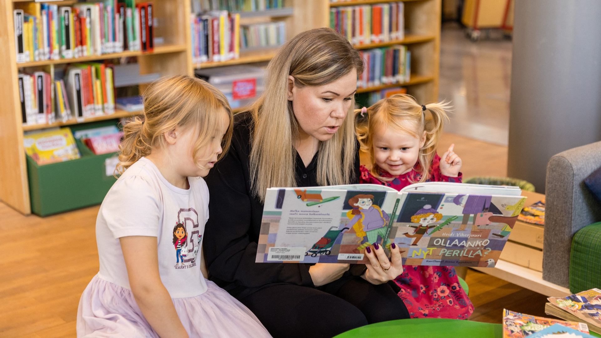 Kvinna som läser bok för två flickor