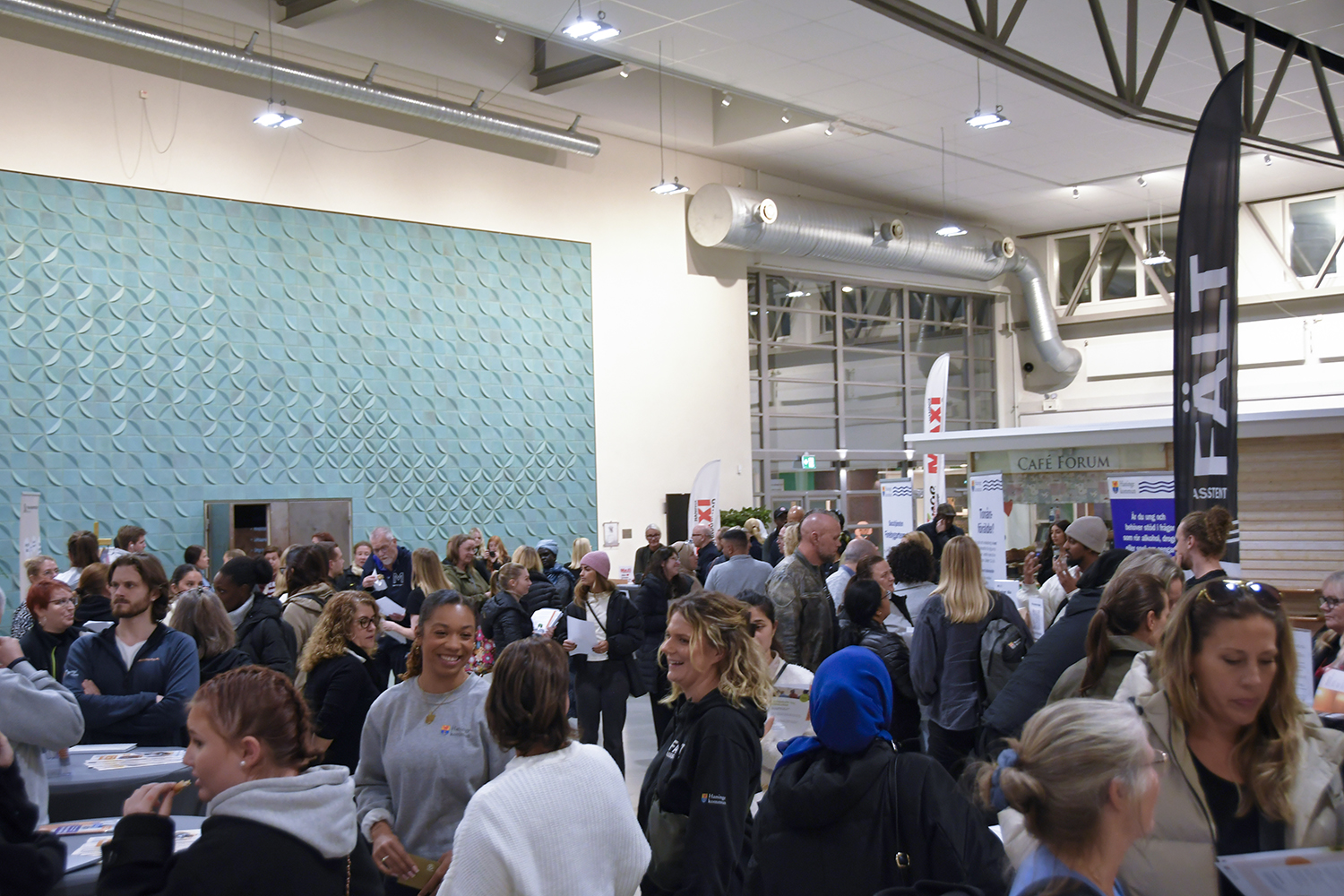 Mingelbild från kvällen där besökare och utställare samlas och samtalar vid olika informationsbord för de olika verksamheterna.