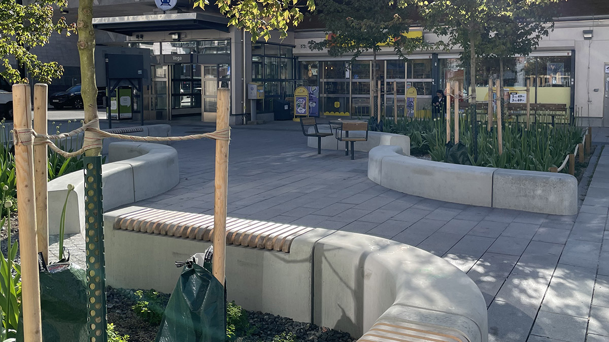 Stenlagt torg med slingrande sittplatser och grönska
