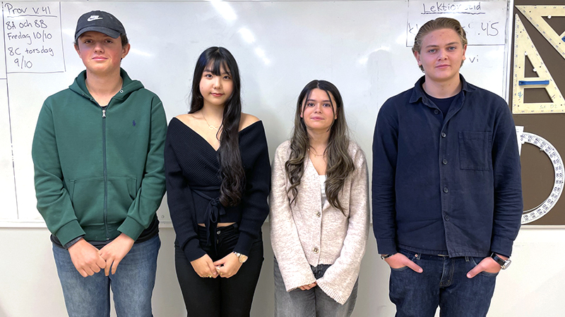 Fyra ungdomar framför en whiteboard i ett klassrum.