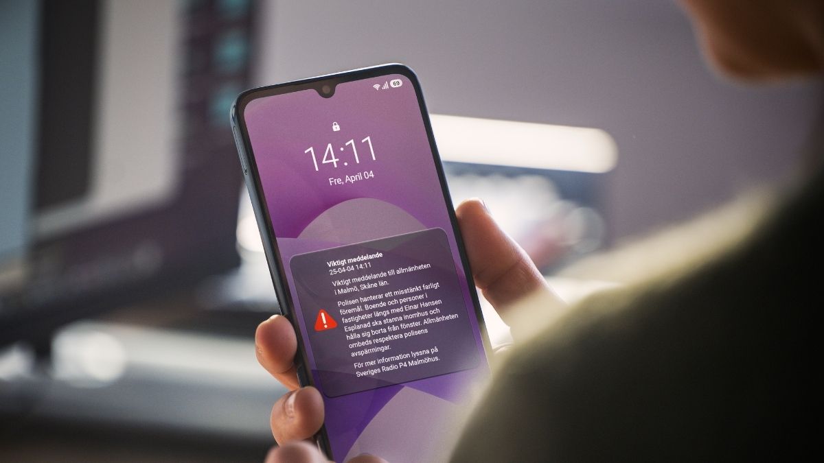 En person håller en smartphone i handen. På skärmen visas ett VMA-meddelande (Viktigt Meddelande till Allmänheten)