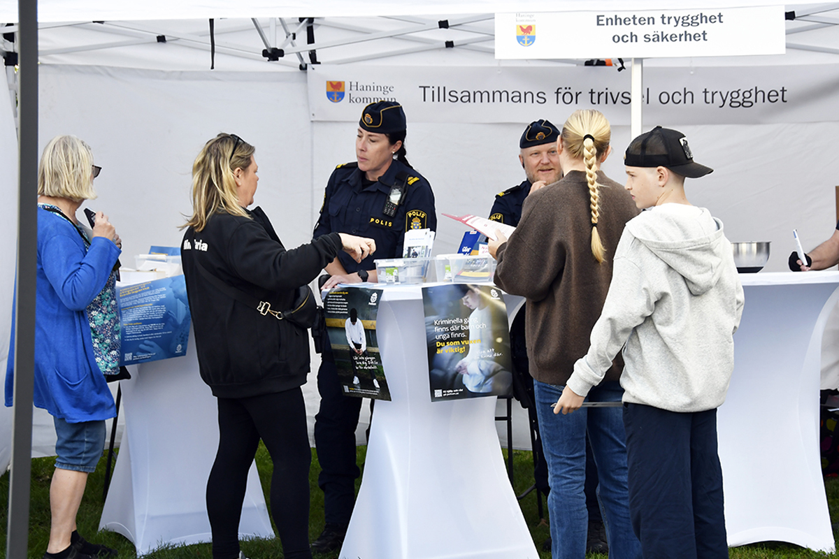 Besökare samlas vid Haninge kommuns informationstält vid ett evemang, där poliser bland annat bemannar och material om trygghet och säkerhet visas.