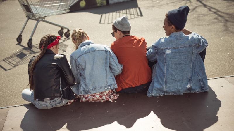 Bild på tonåringar sittandes på trappa, fotograferade bakifrån.