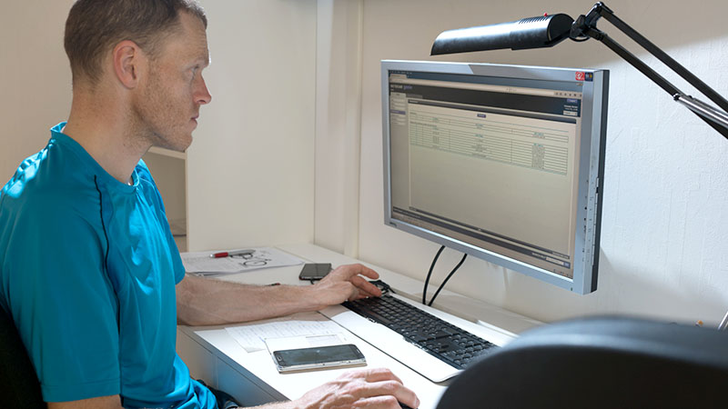 Man som sitter vid sin dator i hemmamiljö