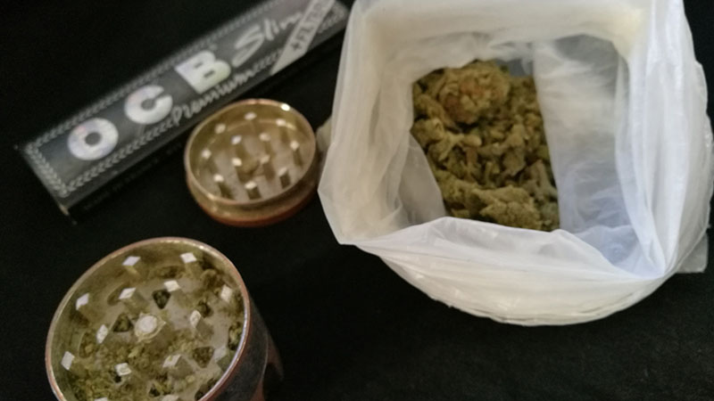 Rullpapper för cigaretter, en örtkvarn och en plastpåse med cannabis