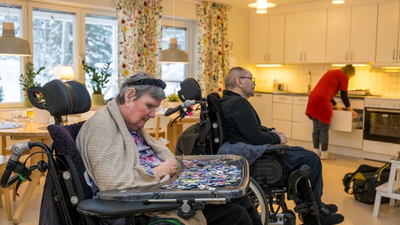 Två personer i rullstol och en personal. 