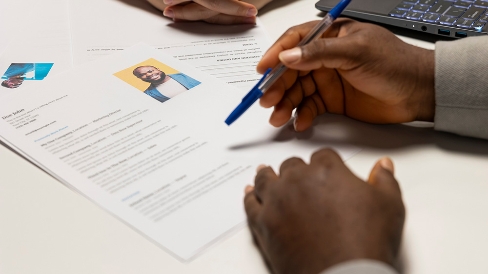 Händer som skriver på ett CV med bild.