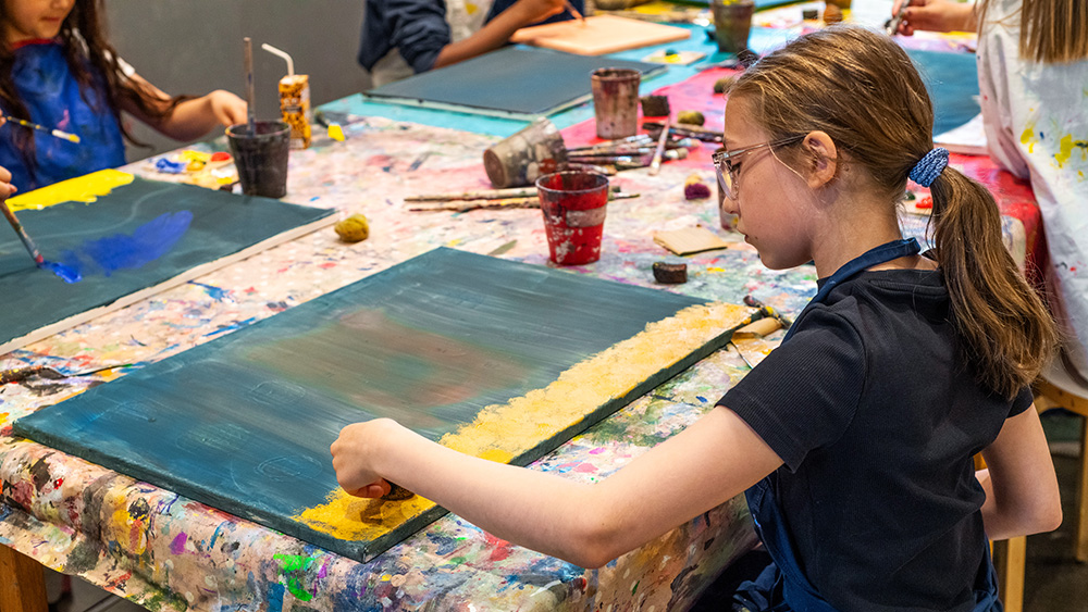 Flicka sitter och målar.