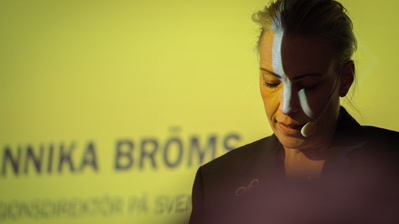 Annika Bröms  på scen, gul powerpoint i bakgrunden